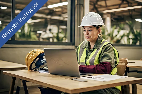 A worker in a hard hat uses a laptop in a classroom setting. A banner indicates a remote instructor.